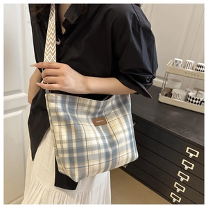 Close-up of stylish plaid crossbody bag with geometric shoulder strap and fashion label