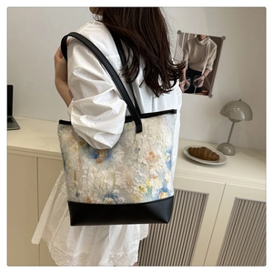 Detail of floral embroidery on a large tote bag with black leather shoulder straps
