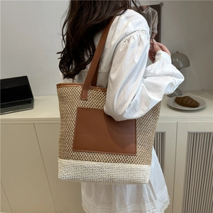 Stylish two-tone straw bucket bag with brown leather patch and long shoulder strap