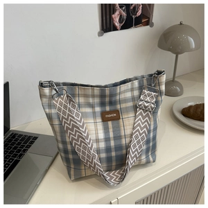 Detailed shot of checkered tote bag with fashion patch and patterned strap on office desk