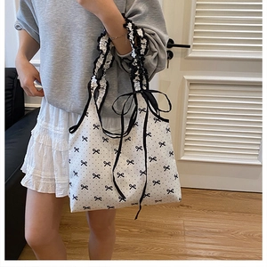 Detailed view of polka dot canvas tote with pleated strap and black ribbon bow detail