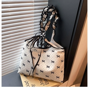Detail of white canvas tote bag with black polka dots, bow prints and ruffled handles