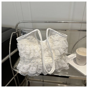 Dettaglio della borsa tote in pizzo bianco con texture a balze su scaffale