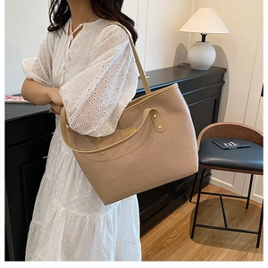 Gros plan du sac cabas kaki avec texture monogramme gaufrée et plaque dorée fashion