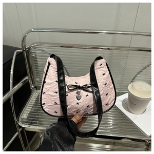 Detail of pink crescent bag with black bow prints and metal heart pendant