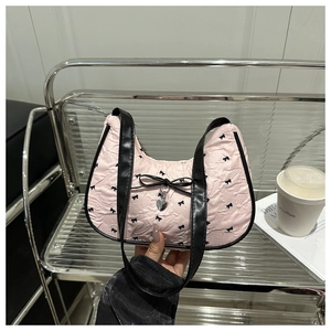 Chic pink pleated crescent bag with black bow prints and metallic heart charm on display