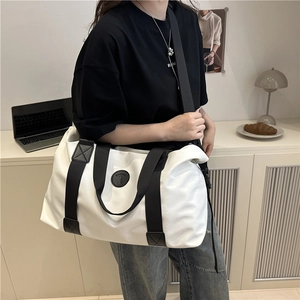 Large capacity white travel tote bag with black strap in a minimalist lifestyle setting