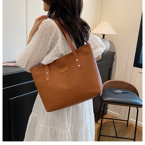 Gros plan du sac cabas marron avec motifs embossés et plaque métallique dorée fashion