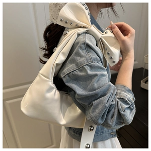 Détail du sac hobo en cuir verni blanc avec rivets argentés et grand nœud sur la bandoulière