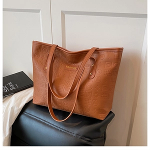 Détail du sac cabas marron avec gaufrage géométrique et plaque dorée élégante en relief