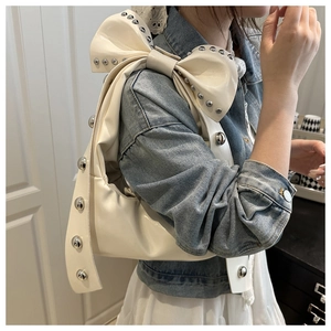 Détail du sac bandoulière blanc en croissant avec rivets argentés et un grand nœud