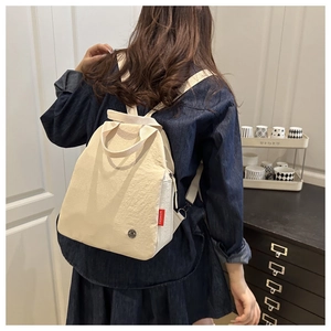 Close-up of beige fashion backpack with a red FASHION tag and metallic logo detail
