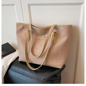 Détail du sac cabas beige avec motifs géométriques gaufrés et plaque logo dorée