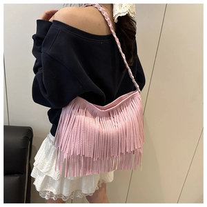 Détail du sac à bandoulière rose à franges avec bandoulière tressée porté par un modèle