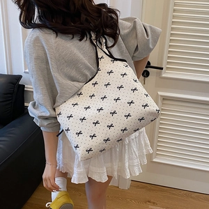 Minimalist white tote bag with black bow and polka dot pattern shown on model