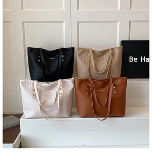 Détail de quatre cabas en cuir gaufré de différentes couleurs avec logo minimaliste