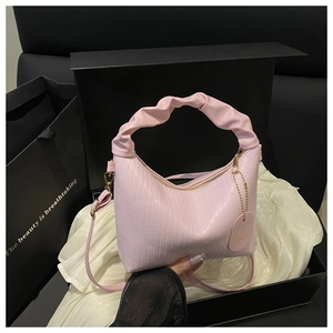 Detailed view of pink pleated handbag with cloud handle and gold zipper in a gift box