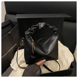Close-up of black pleated faux leather bag with elegant metallic chain and brand tag