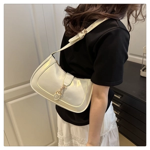 Minimalist white leather hobo bag with gold buckle detail worn by a model