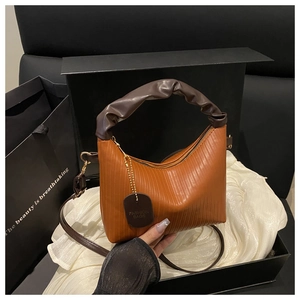 Detail of brown pleated bucket bag with a detachable strap in a premium gift box setup