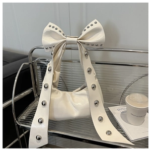 Gros plan du sac à main crème avec nœud et détails de rivets argentés tendance