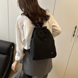 Fashionable black canvas backpack for women with circular logo and large capacity design