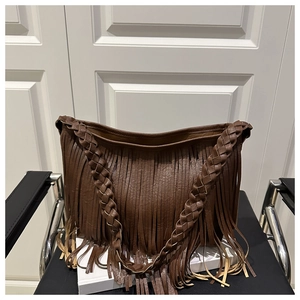 Détail du sac en cuir marron foncé avec de longues franges et une bandoulière tressée