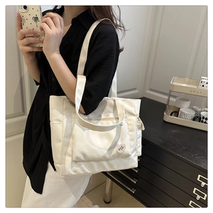 Gros plan du sac fourre-tout blanc avec étiquette Good Luck et poche latérale
