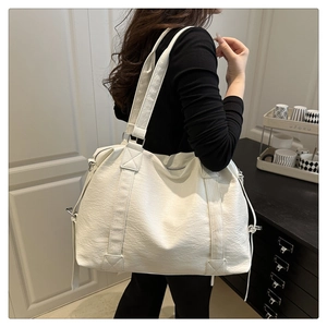 Detail of white faux leather tote bag showing soft lychee texture and side drawstrings