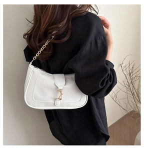 Vue détaillée du sac à bandoulière blanc avec chaîne dorée et boucle métallique sur la sangle