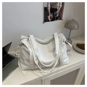 Detailed close-up of a white textured leather tote bag on a minimalist desk with a laptop
