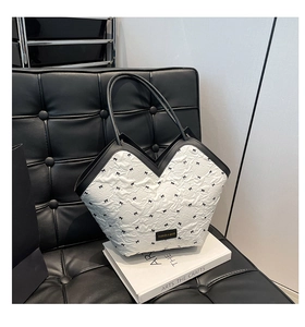Detail of a black and white bow texture tote bag with leather handles on a white book
