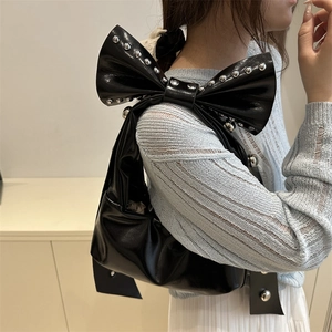 Sac à bandoulière chic en cuir verni noir avec grand nœud clouté et breloques argentées