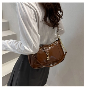 Détail du sac bandoulière en cuir verni marron avec fermoir à piston doré et bandoulière