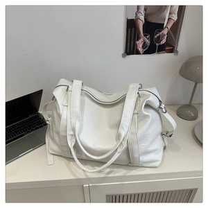 Detail of off-white tote bag showing pebbled leather texture and adjustable strap