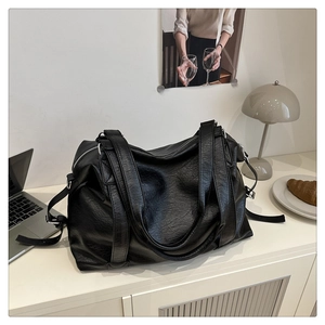 Detail of black faux leather tote bag with silver zipper and large capacity for travel