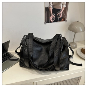 Detail of black faux leather tote bag with metallic zipper and adjustable side buckle