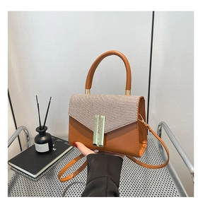 Détail d'un petit sac carré en cuir marron et tissu avec fermoir métallique vertical