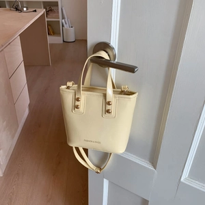 Creamy yellow leather crossbody bucket bag with fashion print and gold rivet details