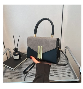 Détail du rabat tissé et de la boucle H dorée sur un sac bandoulière en cuir noir