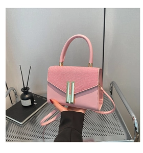 Gros plan d'un sac à bandoulière rose avec boucle dorée et détail de poignée ronde