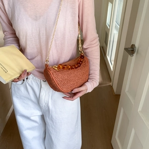 Women's woven straw saddle bag with amber beads and gold chain strap in orange-brown