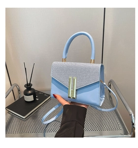 Détail du petit sac bleu clair avec texture tressée et boucle dorée élégante