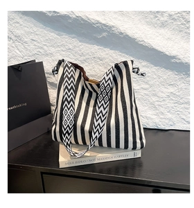Detail of black and white striped canvas tote bag with geometric diamond pattern strap