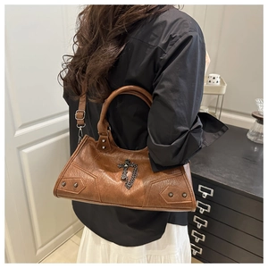 Detail of vintage brown leather handbag with silver rivets and gothic cross charm detail