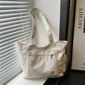 Minimalist cream canvas tote bag with front zipper pocket and 'good luck' patch