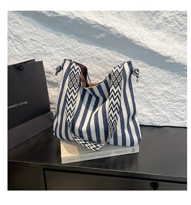 Detail of blue striped canvas tote with jacquard woven strap and drawstring side accents