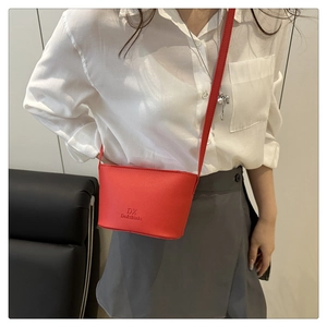 Detail shot of a bright red mini bucket crossbody bag with pebble grain leather texture