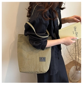 Detailed view of olive green oversized bucket bag with brand label and shoulder strap