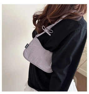 Detail of lilac shoulder bag with subtle wrinkled texture and elegant bow on strap